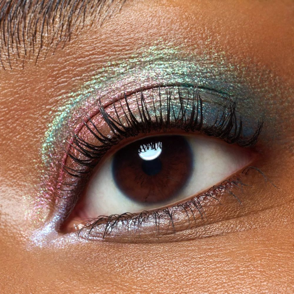 Auge mit grünem und rosa Lidschatten. Wimpern getuscht. Braune Iris.