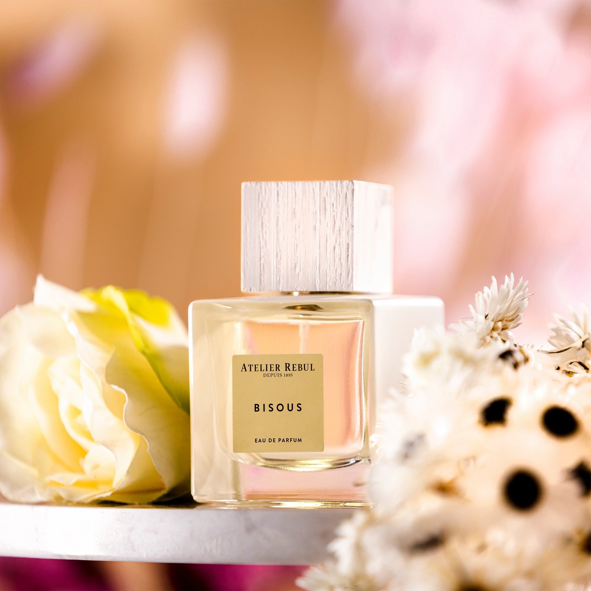 Glasflasche mit Holzdeckel, umgeben von Blumen. Auf dem Etikett steht "Bisous".