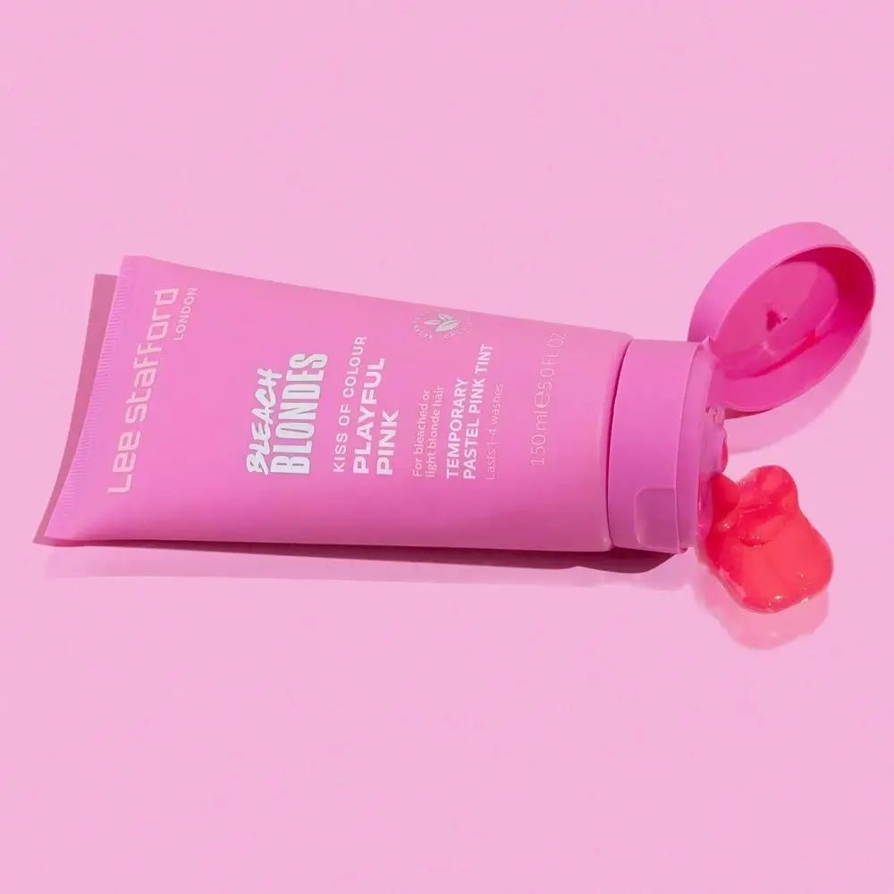 Rosa Tube liegt. Produkt wird herausgedrückt. Rosa Flüssigkeit auf rosa Untergrund.