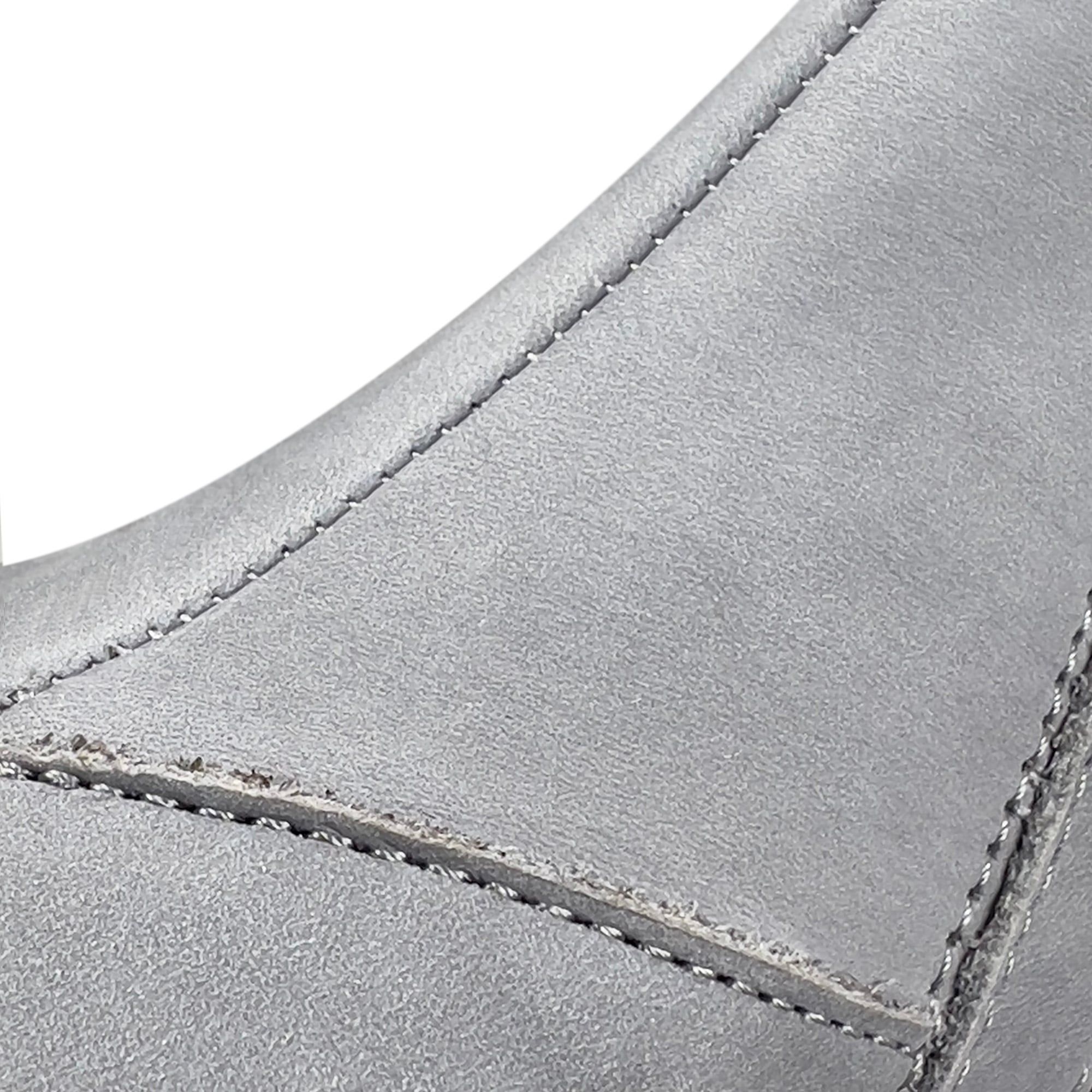 Nahaufnahme von Nähten an einem grauen Damen-Slipper. Sichtbare Nähte, graues Obermaterial, Detailansicht.