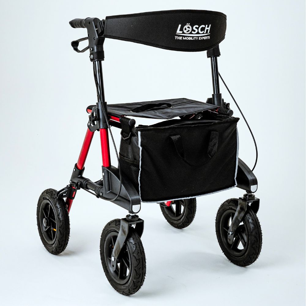 Rollator mit schwarzem Sitz, Tasche und Rückenlehne. Roter Rahmen, vier Räder. Marke: Lösch.