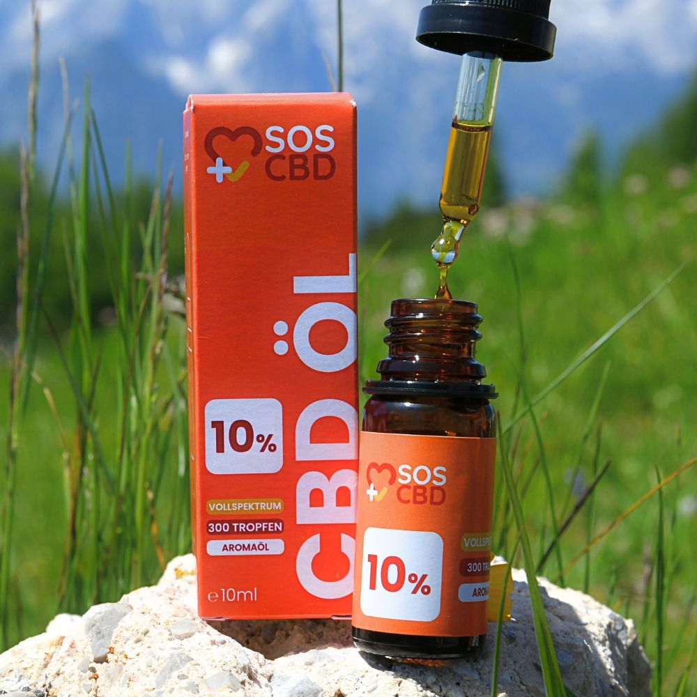 Braune Glasflasche mit schwarzem Tropfer und Tropfen. Orangefarbene Verpackung. Hintergrund: grüne Wiese und Berge. Text: CBD Öl 10%.