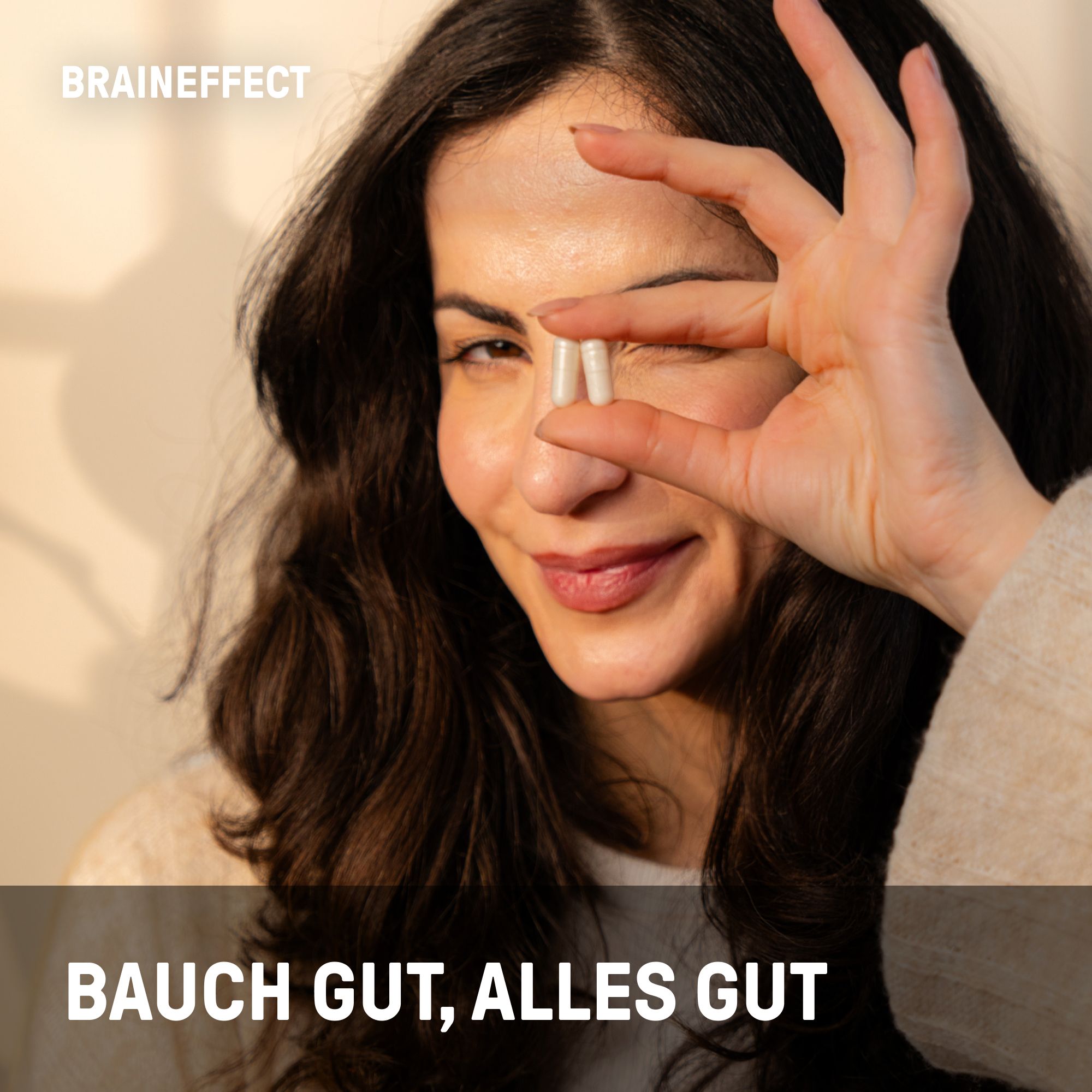 Frau hält zwei Kapseln vor dem Auge. Text: BAUCH GUT, ALLES GUT. BRAINEFFECT Logo.