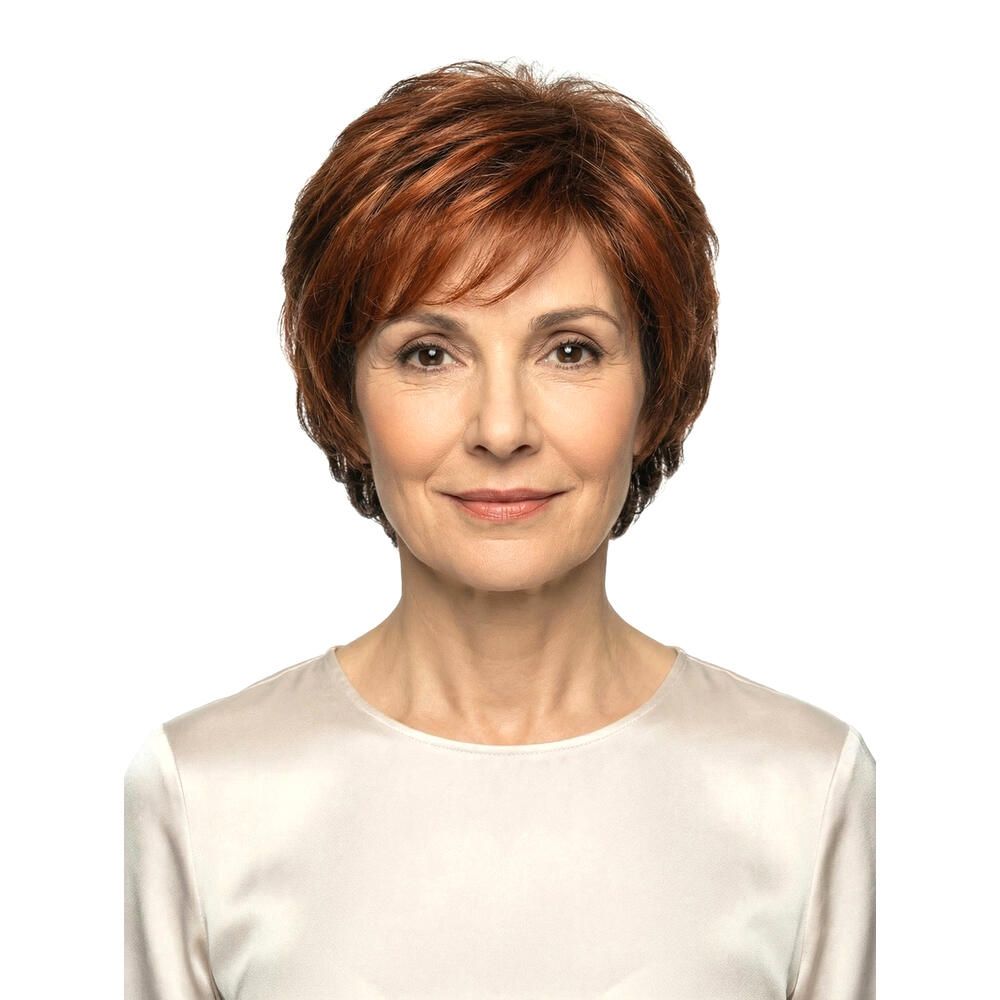 Frau mit rotbrauner Perücke. Frontale Ansicht. Kurze, gewellte Haare. Helle Haut, weißes Oberteil. Blick in die Kamera.
