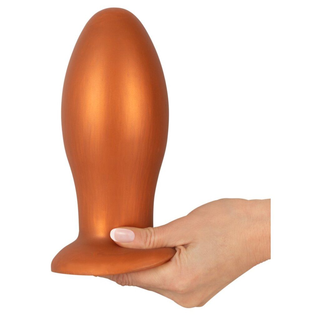 Orangefarbener, weicher Butt Plug. Runde Basis, konische Form. Wird von einer Hand gehalten.