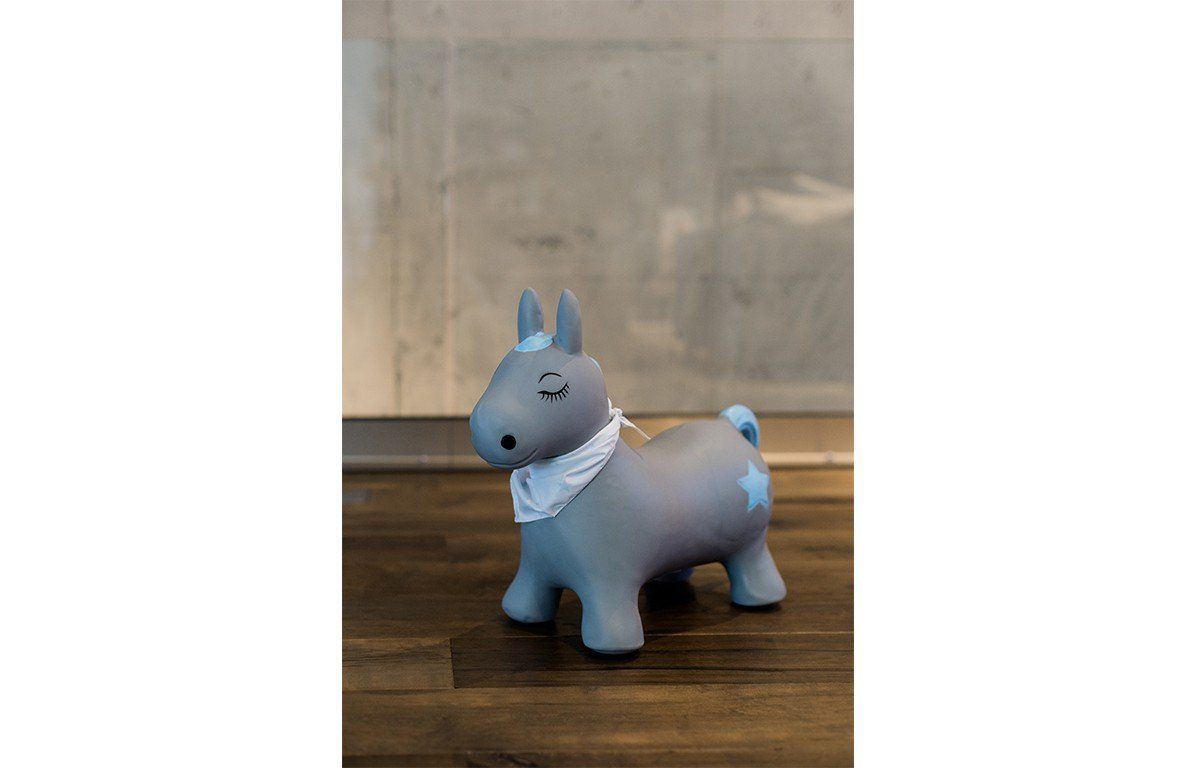 Graues Hüpftier Pony mit blauen Akzenten und Sternenmuster. Es hat ein Halstuch und geschlossene Augen.