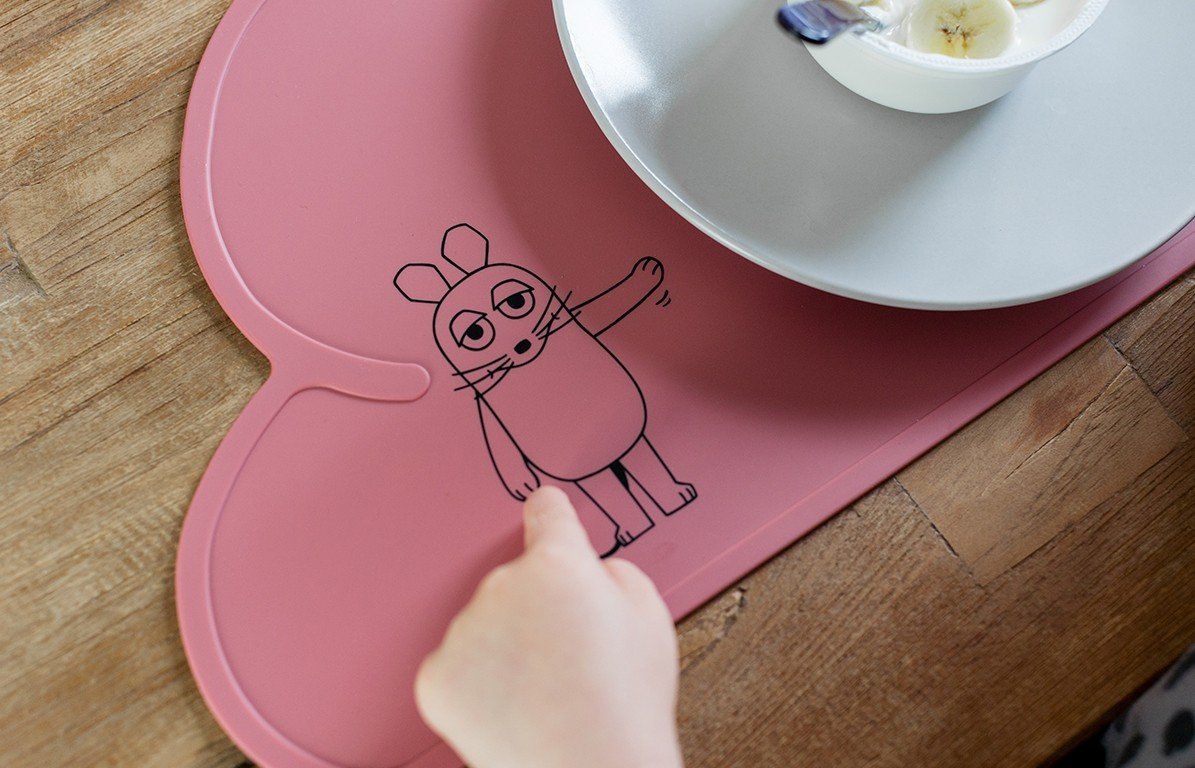 Rosa Platzdeckchen in Wolkenform mit Maus-Illustration. Hand zeigt auf das Deckchen.