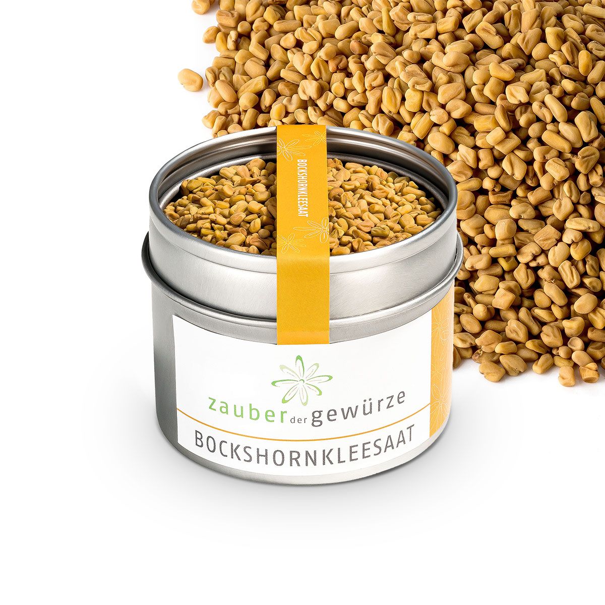 Zylindrische Dose mit Bockshornklee Saat. Aufkleber mit Produktname und Logo. Gelbes Etikett mit Produktname. Streuung von Samen daneben.