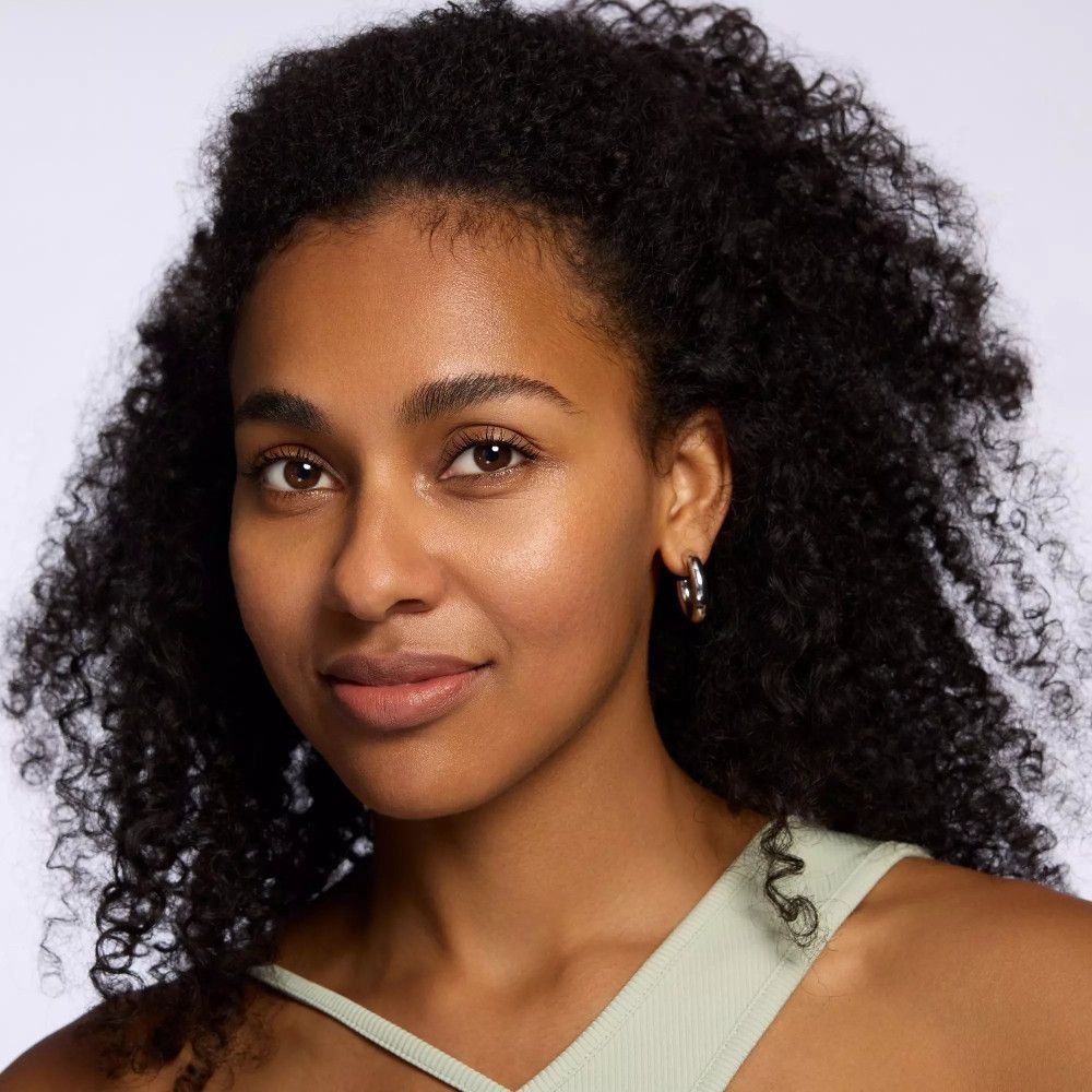 Porträt einer Frau mit Locken und Lippenstift. Sie trägt Ohrringe. Natürliches Make-up.