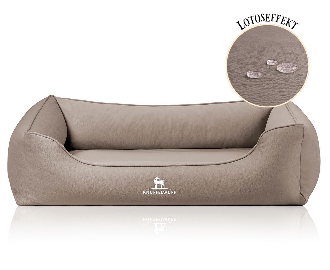 Beiges orthopädisches Hundebett mit erhöhtem Rand. Logo: Knuffelwuff. Detail: Wassertropfen auf der Oberfläche, Hinweis auf Lotuseffekt.