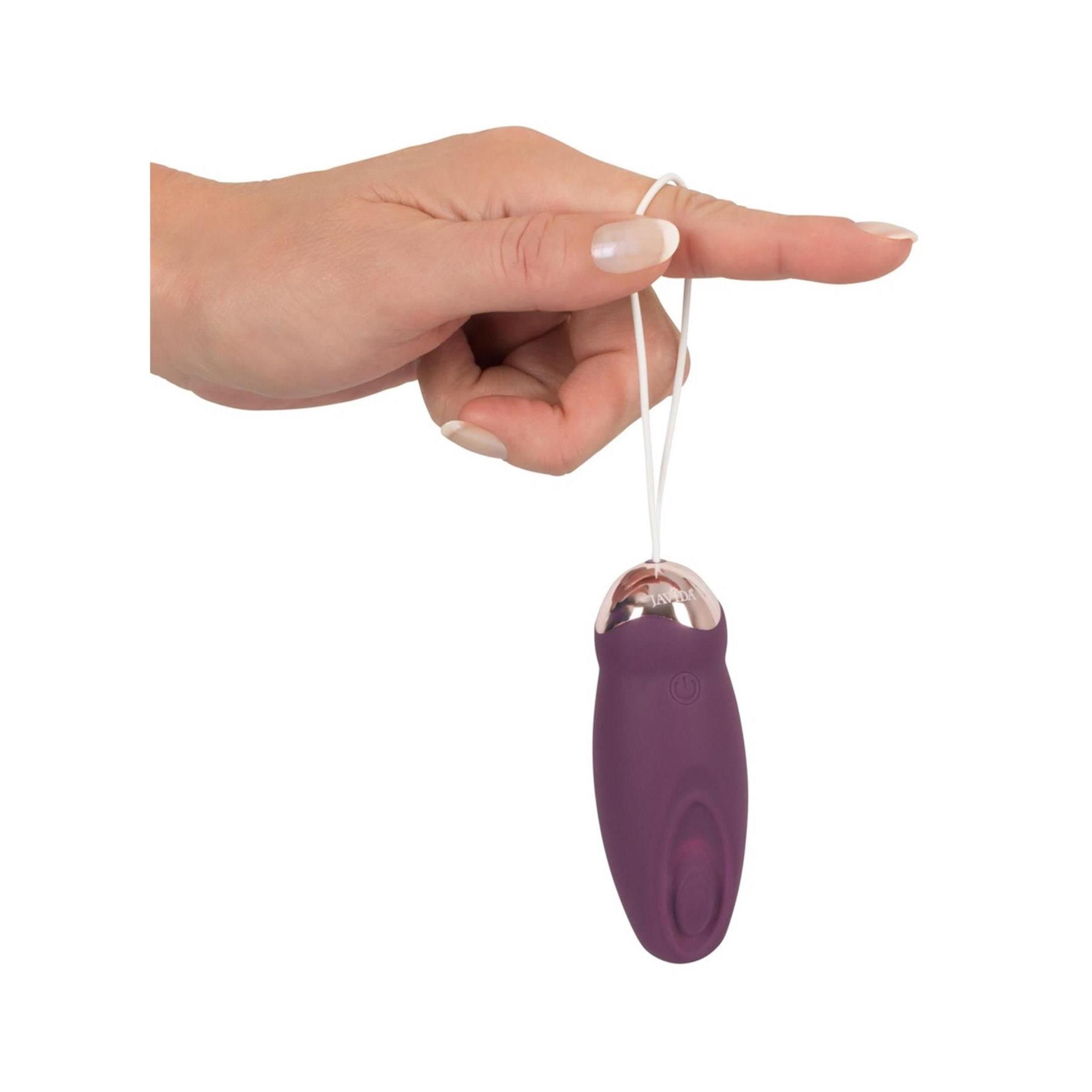 Hand hält Vibrationsgerät mit weißer Schlaufe. Auf weißem Hintergrund.