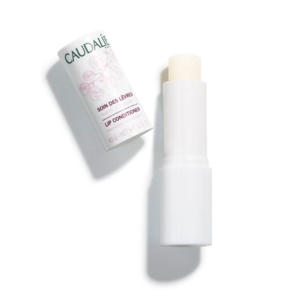 Geöffneter Lippenpflegestift mit weißer Hülle und freiliegendem Pflegestift. Daneben die Kappe.