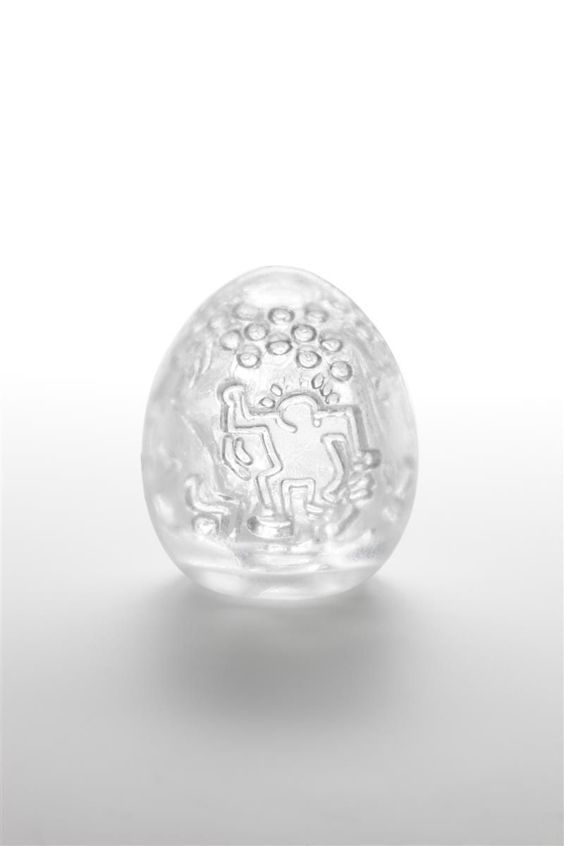 Durchsichtiges, eiförmiges Produkt mit Relief von Figuren. Oberseite mit kleinen Kreisen. Auf hellem Hintergrund.