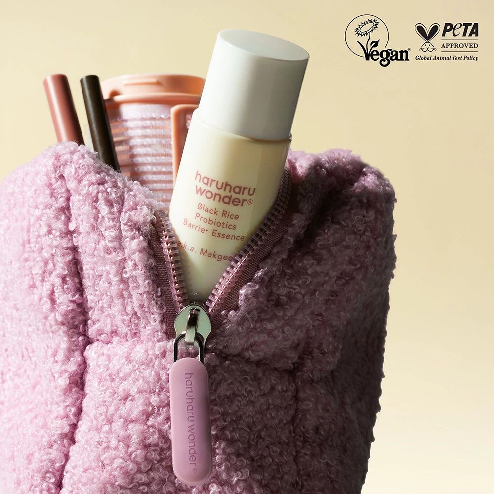 Beige Flasche in einer rosa Tasche. Aufschrift: haruharu wonder Black Rice Probiotics Barrier Essence. Vegan- und PETA-Siegel.