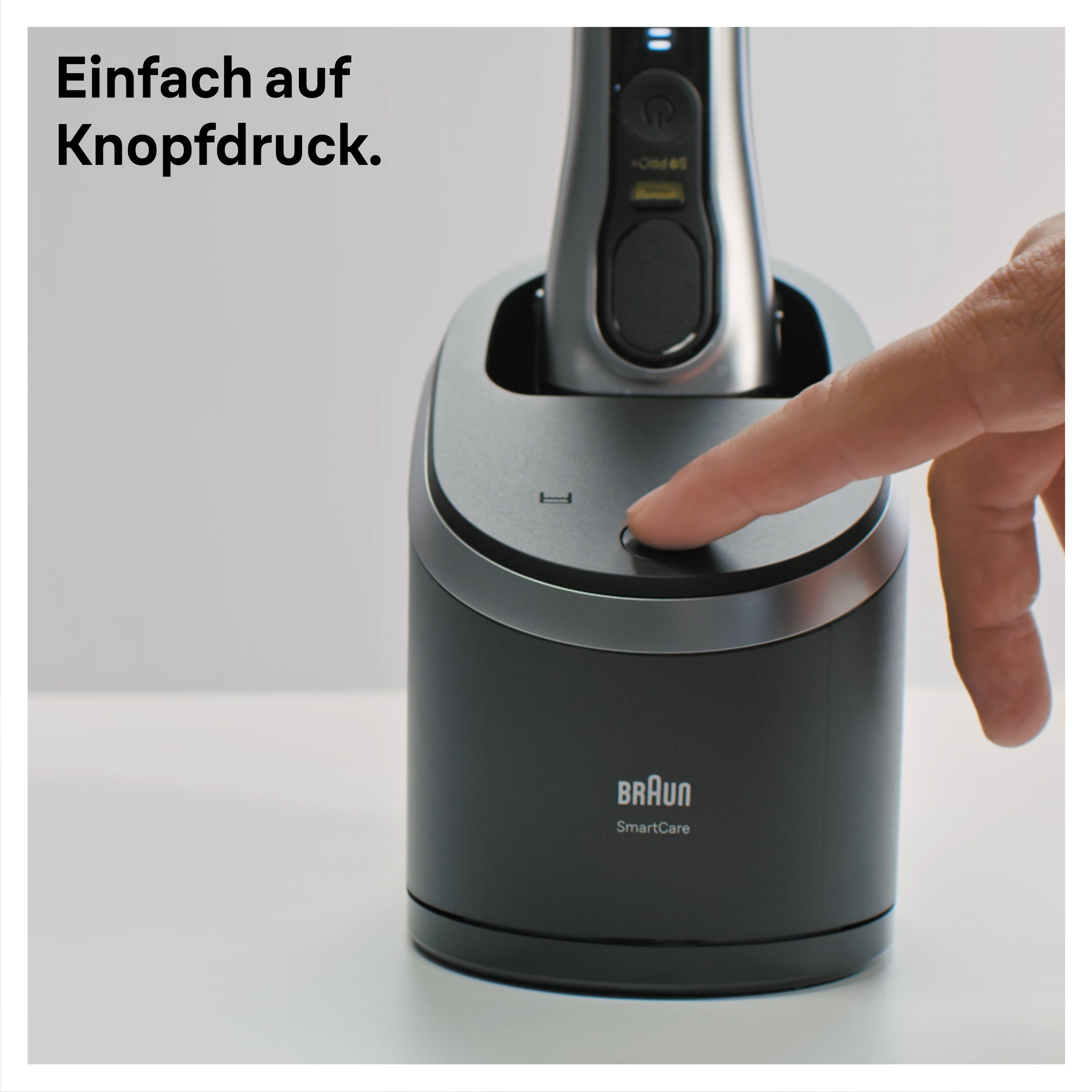 Hand drückt Knopf auf einer schwarzen Reinigungsstation. Text: Einfach auf Knopfdruck. Braun SmartCare-Logo.