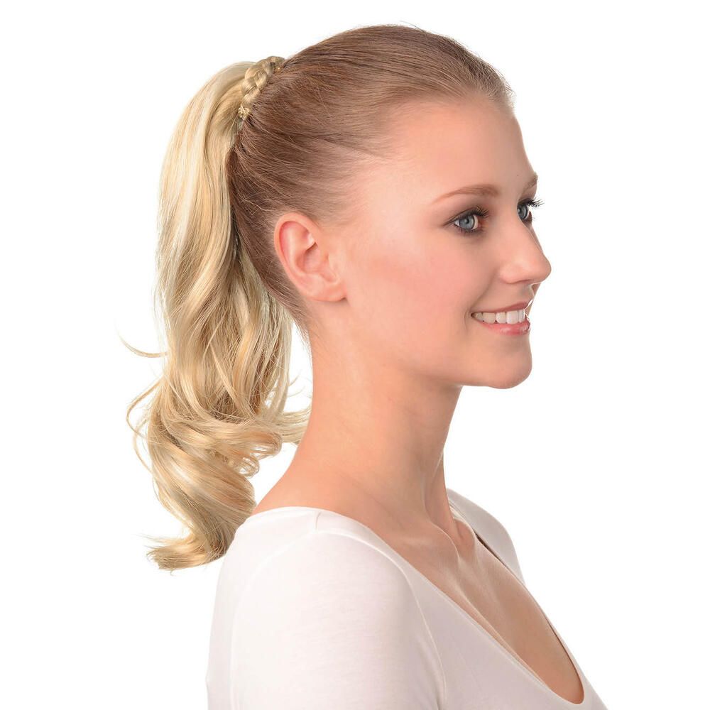 Blondes Haarteil, als Pferdeschwanz getragen. Welliges Haar, am Hinterkopf befestigt. Frau trägt weißes Oberteil.