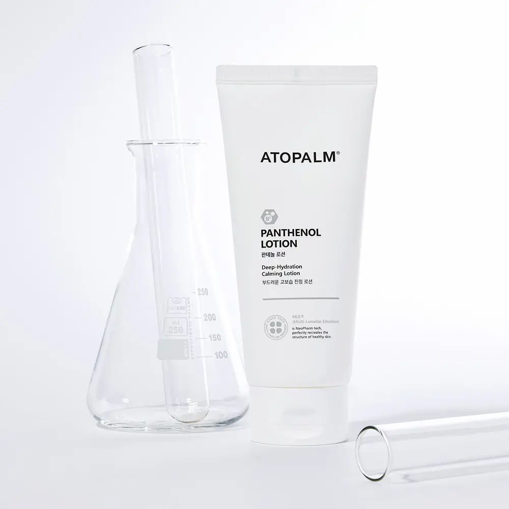 Weiße Tube mit ATOPALM Panthenol Lotion. Daneben Glasbehälter und Reagenzglas. Aufschrift: Deep Hydration Calming Lotion.
