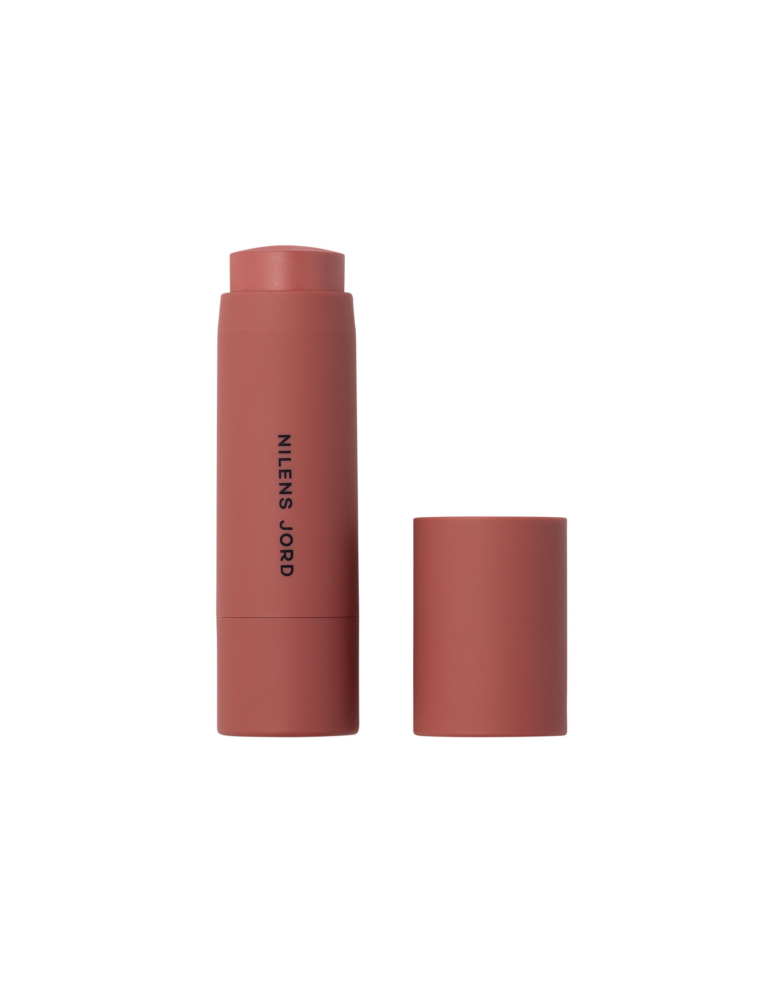 Nilens Jord Cheeks & Lips Stick, rosafarbener Behälter mit abgenommenem Deckel.