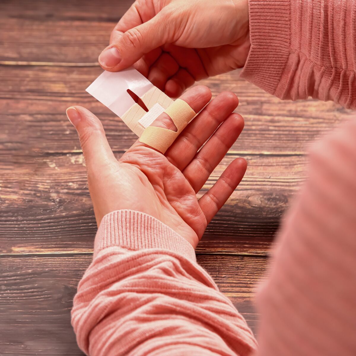 Person wendet ein WERO MasterTex Fingergelenkpflaster auf den Finger an. Einzeln verpackt.