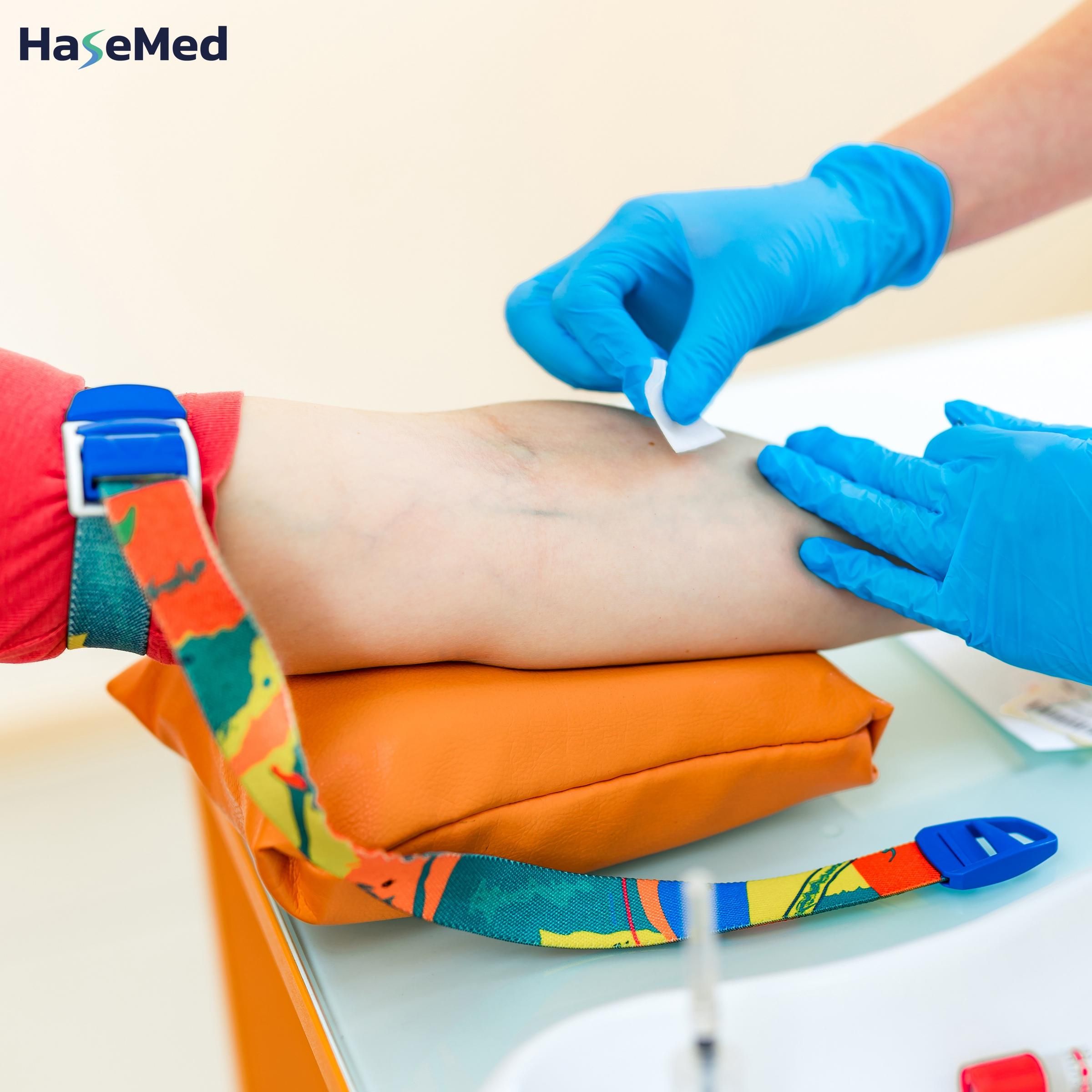 Arm mit Venenstaugerät. Medizinische Fachkraft bereitet Injektion vor. Marke: HaseMed.