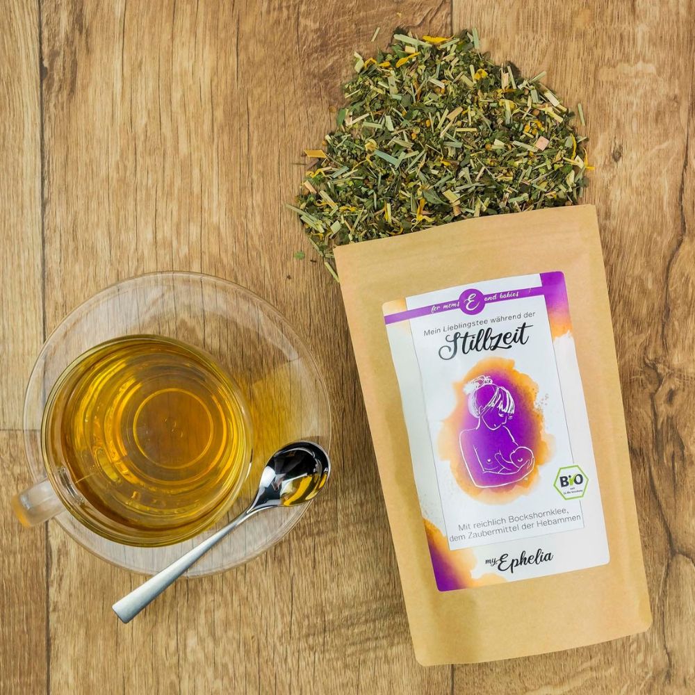 Tasse Tee, Löffel, Teeblätter, Beutel mit Etikett. Etikett: Mein Lieblingstee während der Stillzeit. Marke: myEphelia. Bio-Siegel.