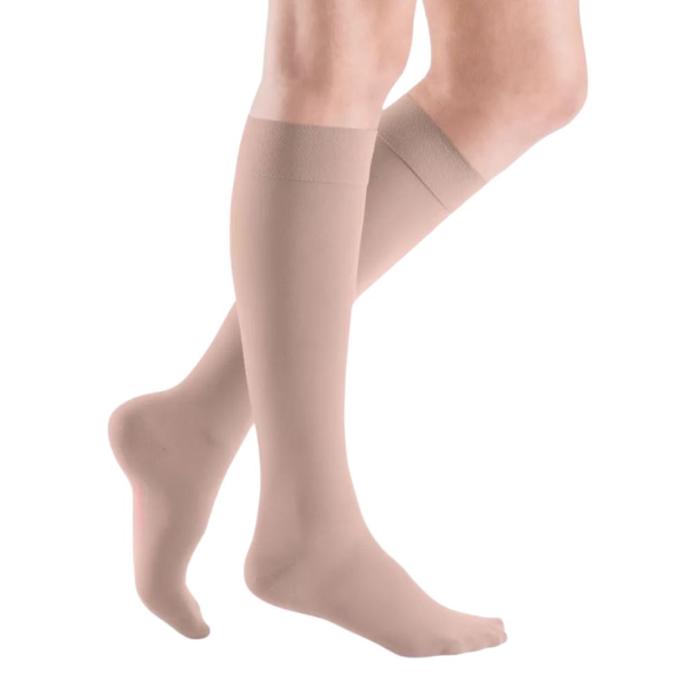 Beige Kompressions-Kniestrümpfe an Beinen. Feines, glattes Material. Nahtloser Abschluss am oberen Rand.