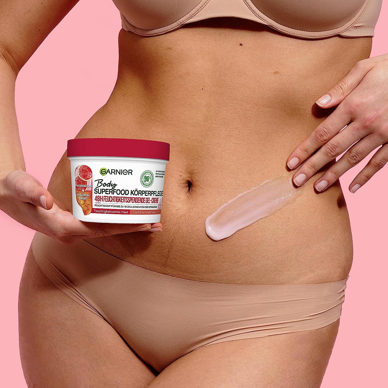 Frau hält Tiegel und trägt Creme auf den Bauch auf. Text: 48h Feuchtigkeit.