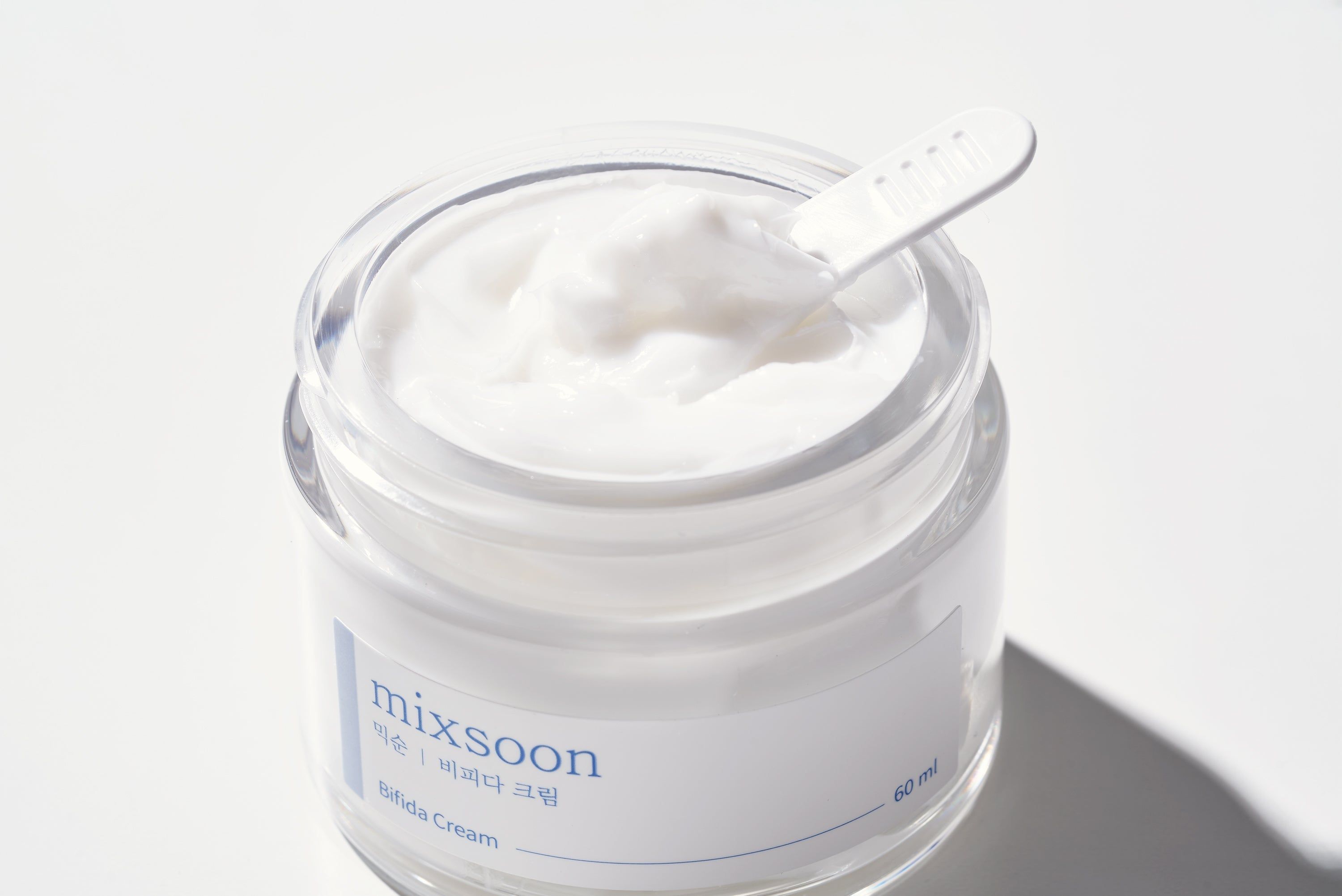 Offenes Cremeglas mit Creme und Spatel. Aufkleber mit "mixsoon Bifida Cream".