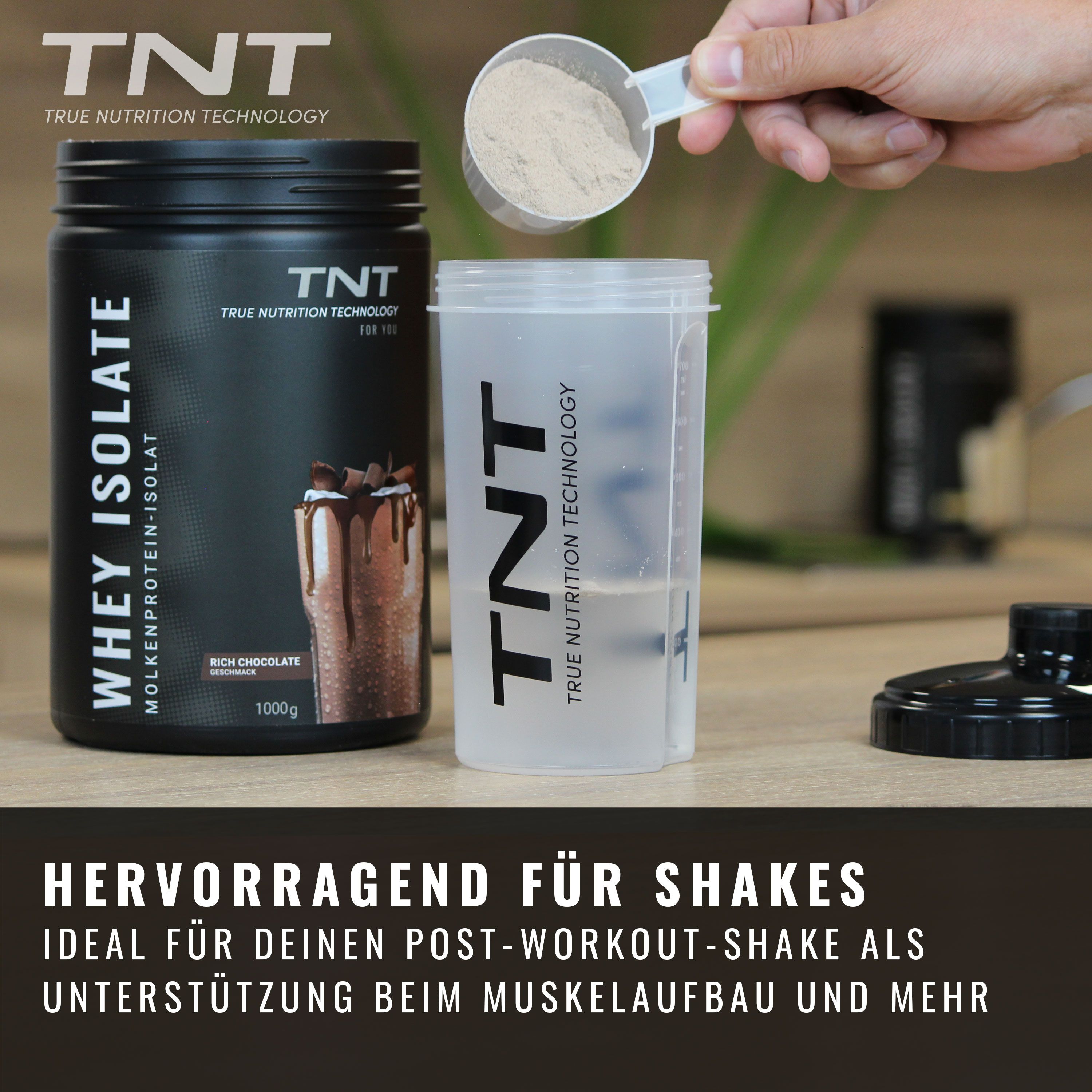 Dose TNT Whey Isolate neben Shaker. Löffel mit Pulver. Produktname und Logo deutlich sichtbar.