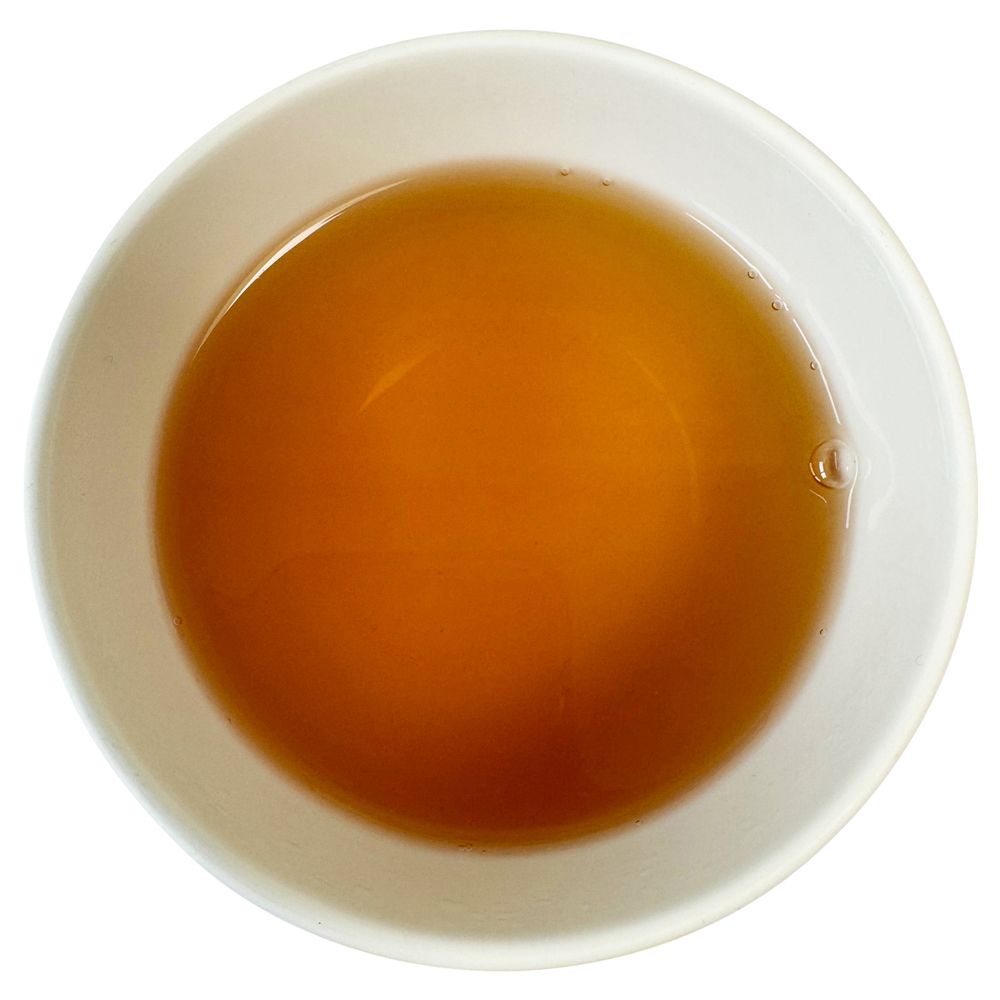 Tasse mit bernsteinfarbenem Getränk. Draufsicht.