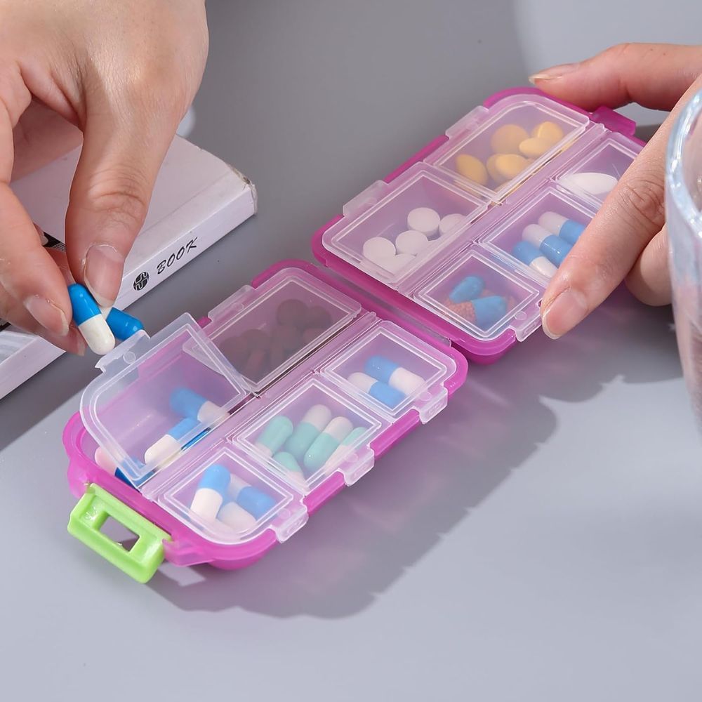 Pinke Pillendose mit 8 Fächern, gefüllt mit verschiedenen Pillen und Kapseln.