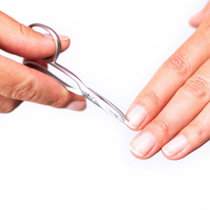 Nagelschere für Linkshänder schneidet einen Fingernagel. Die Schere ist aus Metall und wird von einer Hand gehalten.