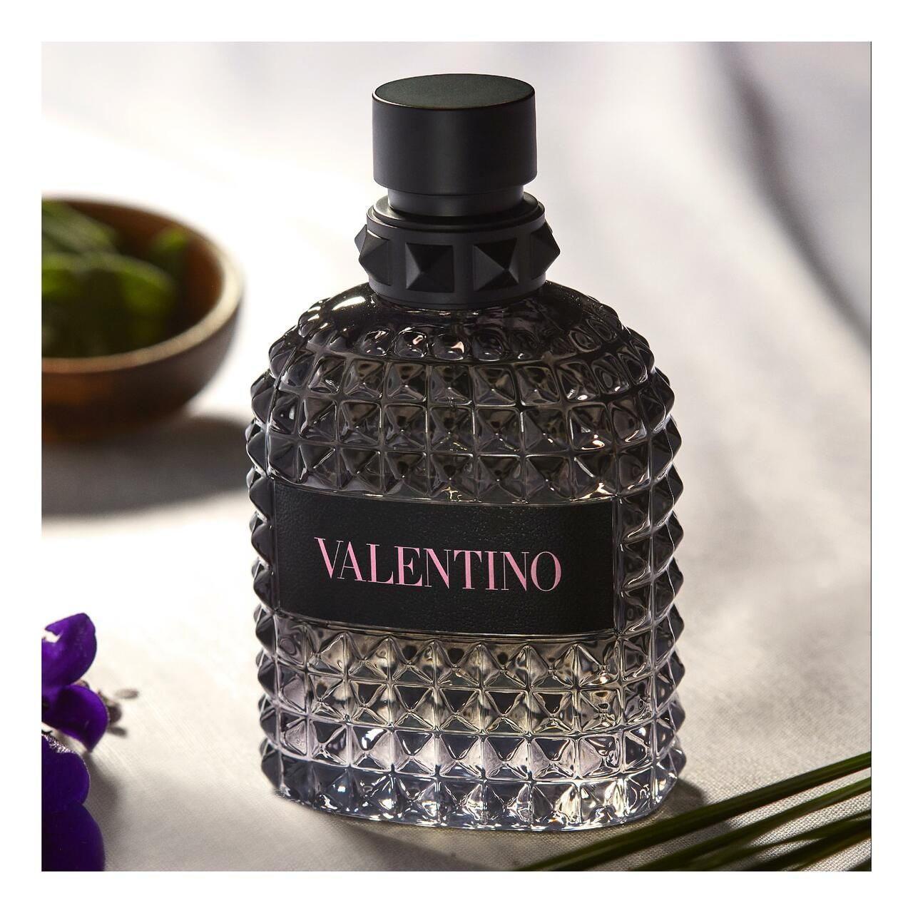 Schwarzer Flakon mit rosa Schriftzug VALENTINO. Geometrisches Muster. Hintergrund mit Dekoration.