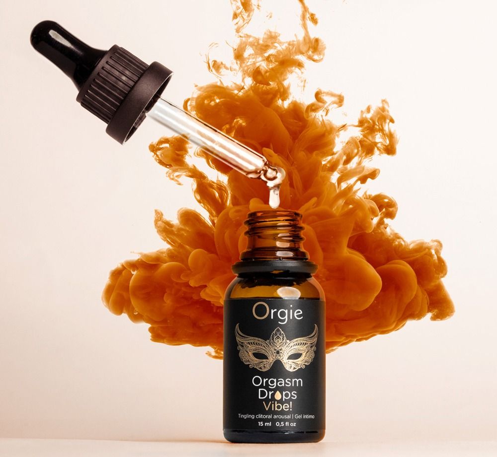Braune Flasche mit Tropfer. Produktname: Orgie Orgasm Drops Vibe! Tropfen fallen in die Flasche. Hintergrund: orangefarbener Rauch.