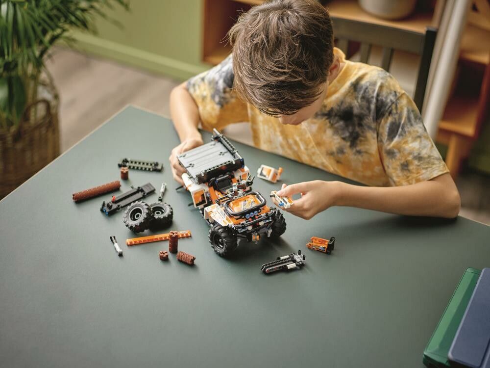 Un bambino assembla il LEGO Technic Fuoristrada. Il modello è parzialmente assemblato. Vari pezzi e strumenti sono sul tavolo.