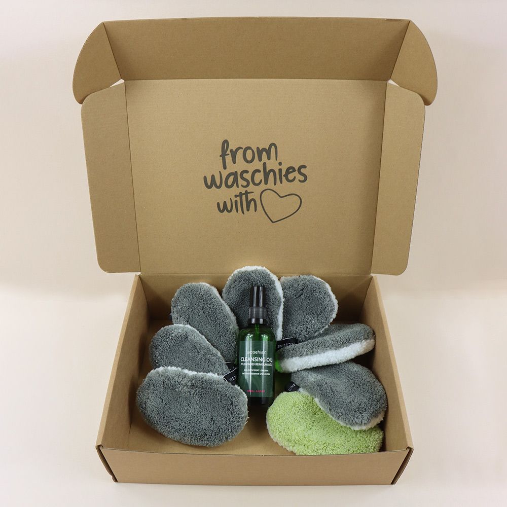 Offene Box mit Reinigungsöl, Waschies-Schwämmen und Waschies-Waschpads. Text: from waschies with ❤️. Waschies-Logo.