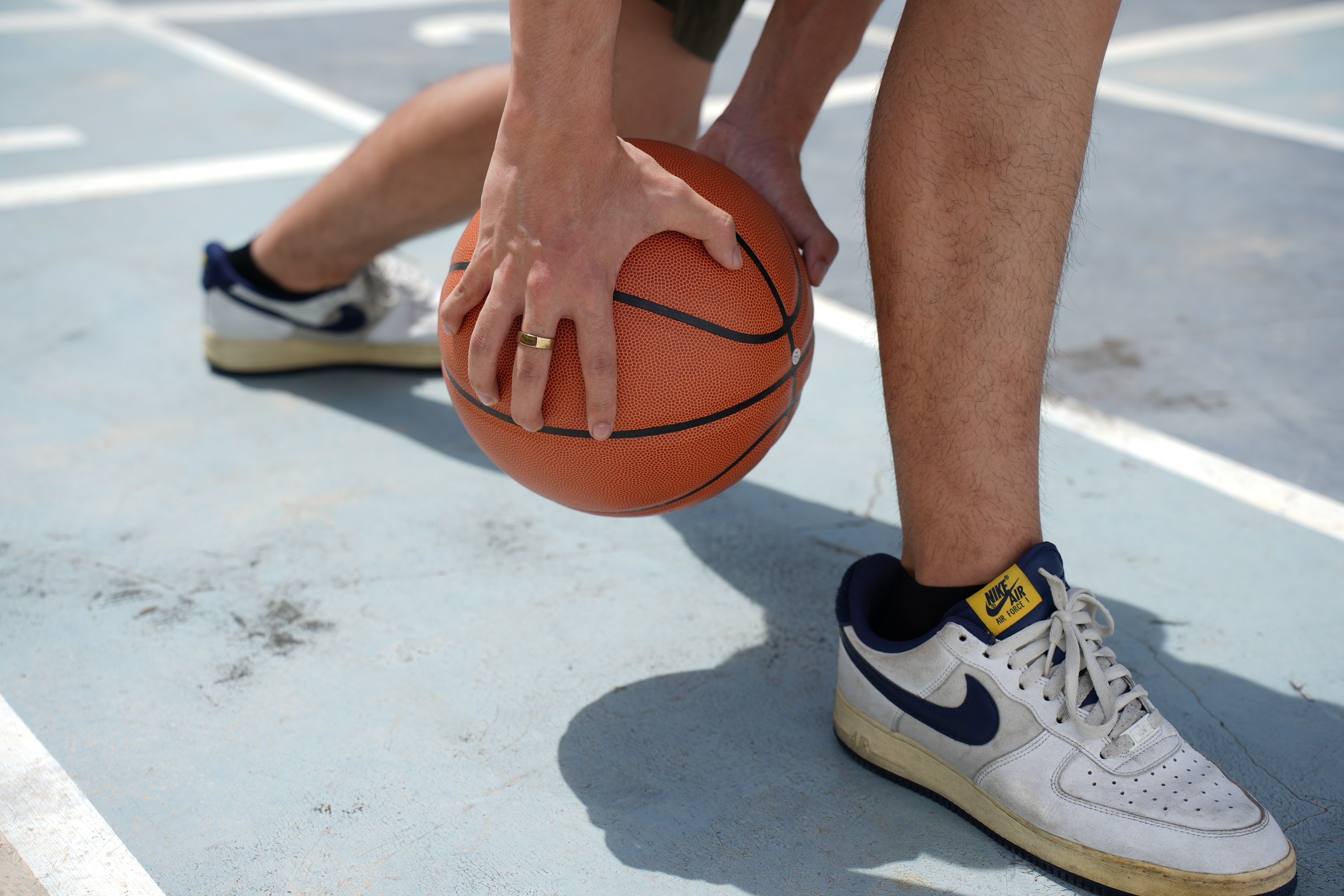 Mann mit Basketball und goldenem Ring. Er trägt Turnschuhe.