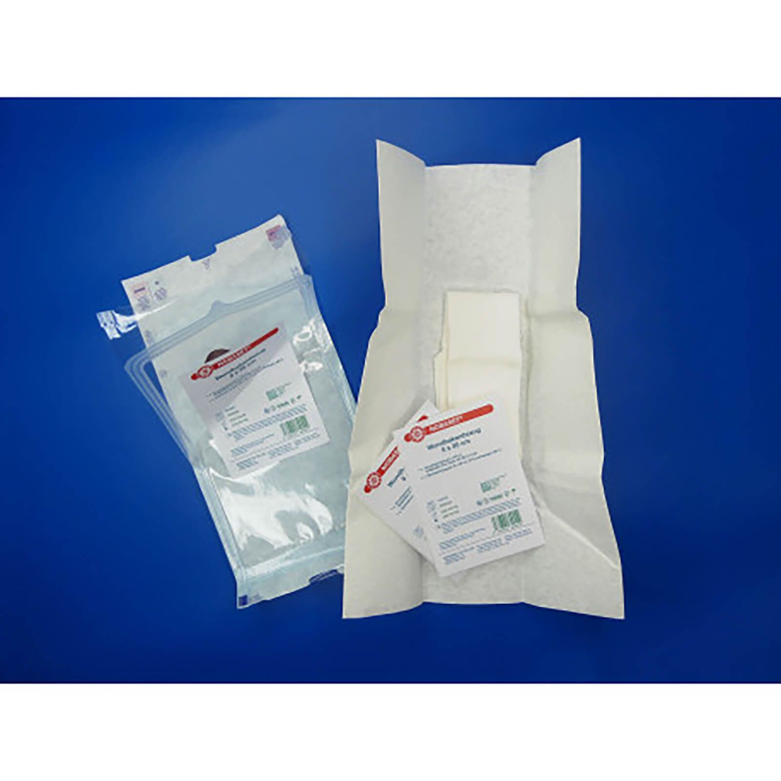 NOBA Nobaset® Wundhakenbezug, geöffnet. Einzelne Bezüge und Verpackung mit Etikett. Weißes Material, teilweise gefaltet. Auf blauem Hintergrund.