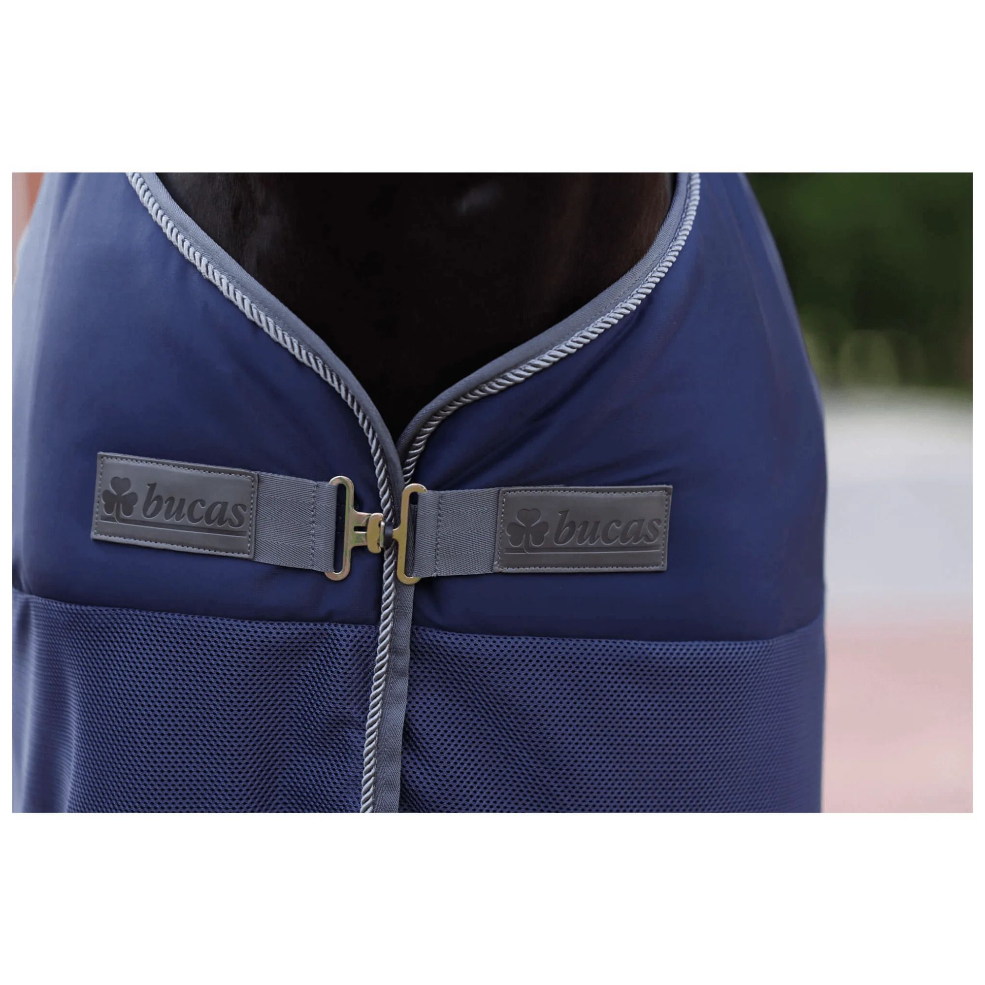 Nahaufnahme der Pferdedecke. Dunkelblau mit Logo und silberner Kante. Verschluss mit Schnalle.
