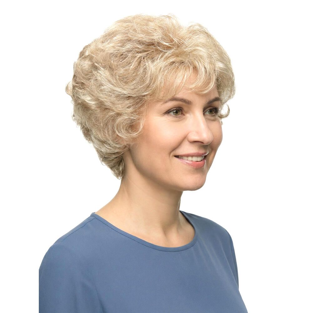 Blond gelockte Perücke. Nahaufnahme einer lächelnden Frau mit blauem Oberteil. Kurze, wellige Frisur.