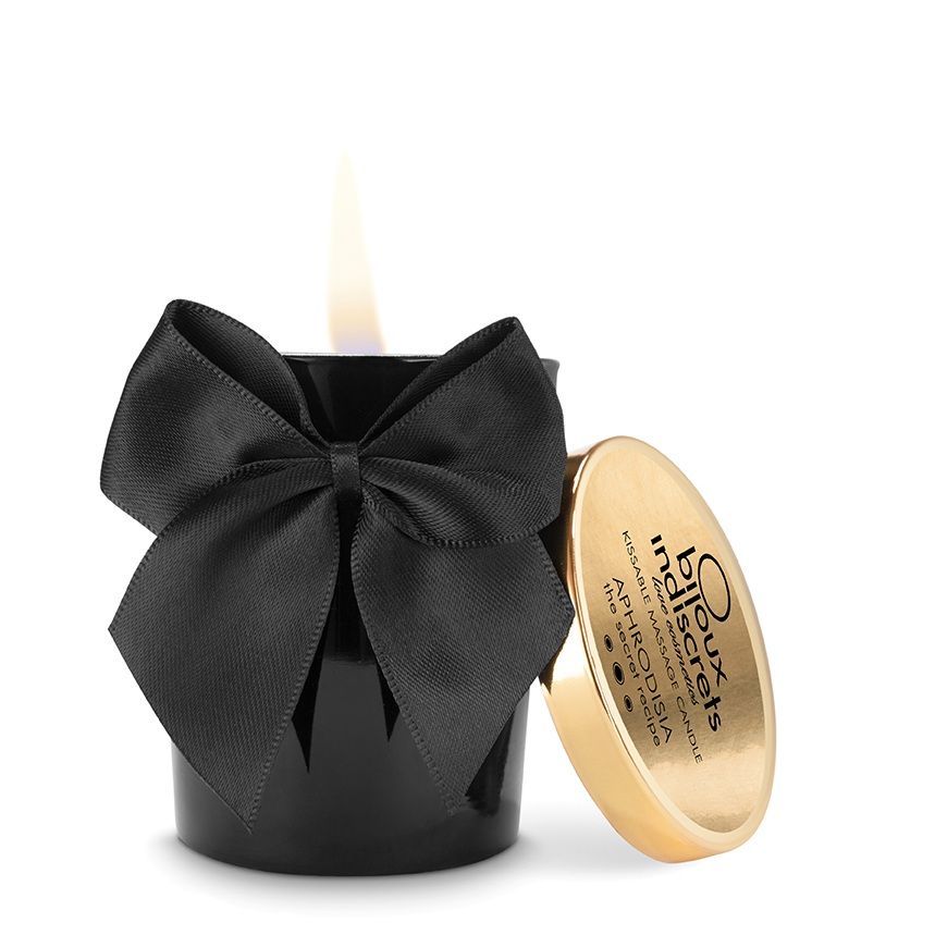 Schwarze Kerze mit Schleife und Deckel. Goldener Deckel mit Schriftzug. Flamme brennt. Produktname: Bijoux Indiscrets.