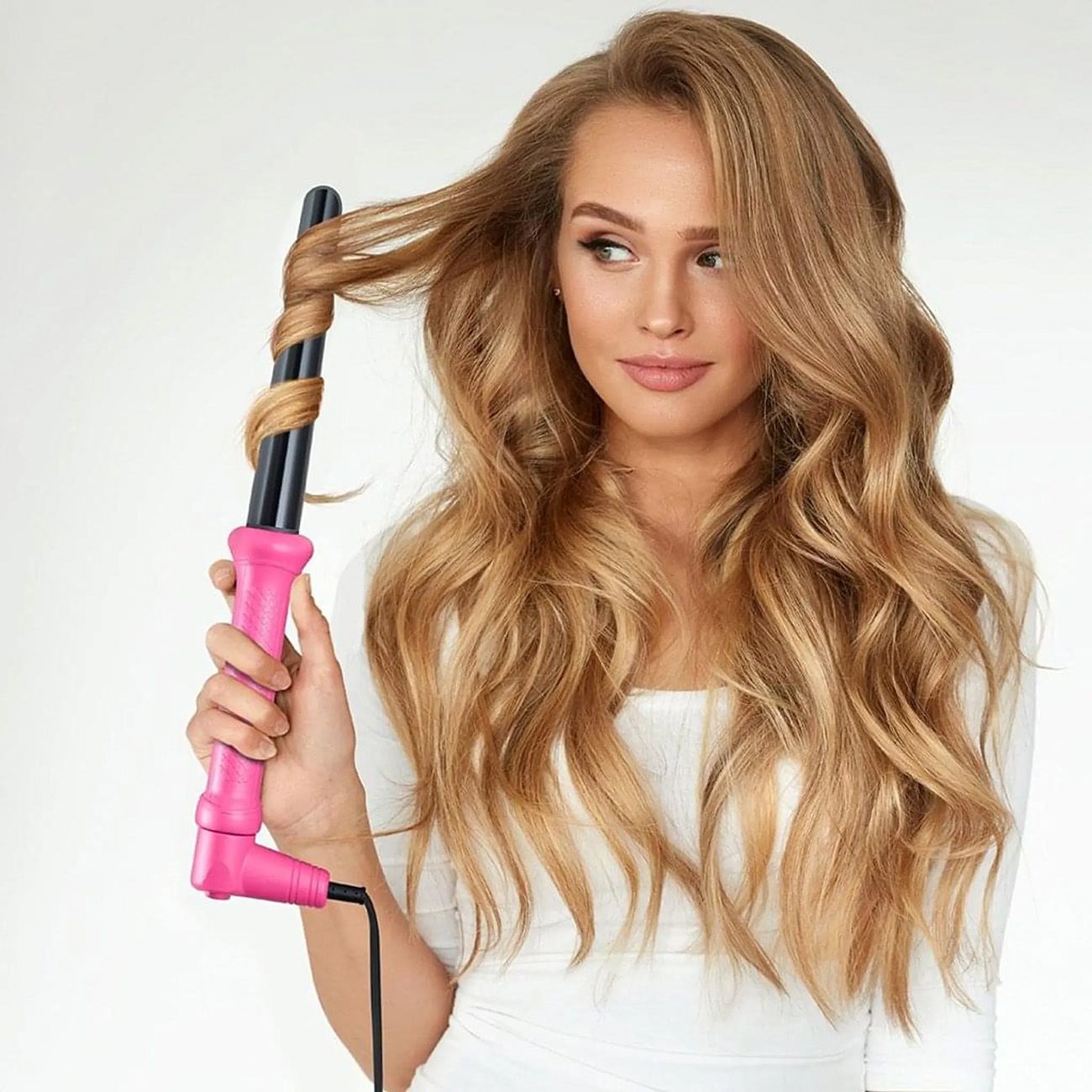 Frau mit Lockenstab. Frau hält Lockenstab mit pinkfarbenem Griff. Blondes Haar wird gelockt.