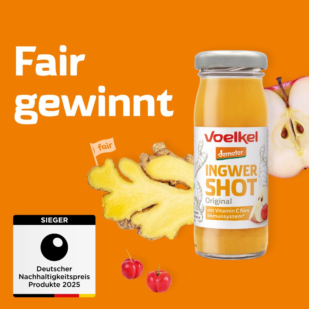 Glasflasche mit gelbem Saft, Etikett "Voelkel Ingwer Shot Original". Text: Vitamin C fürs Immunsystem. Ingwer, Apfelhälfte, Fair-Logo, Nachhaltigkeitspreis.