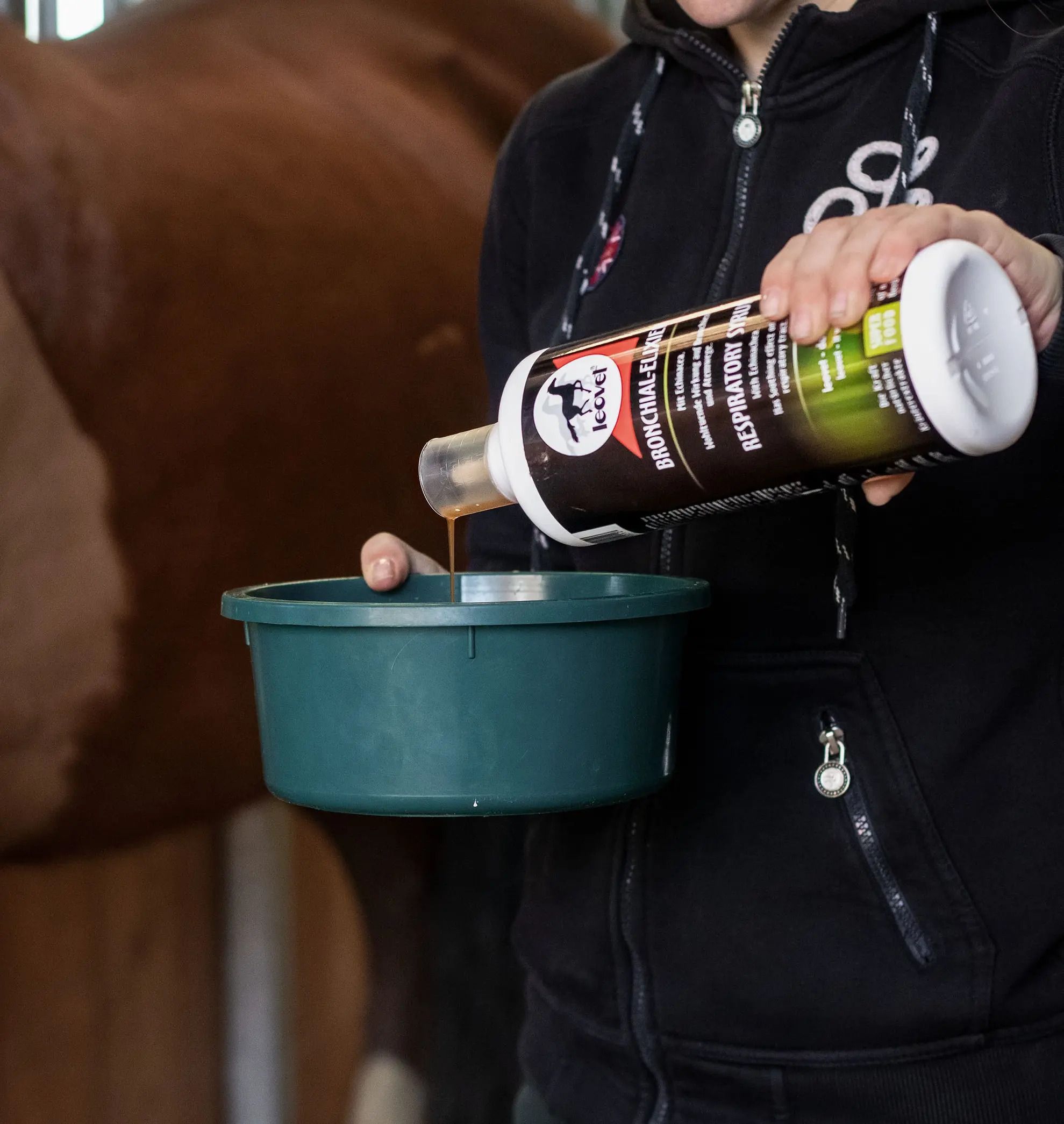 Flasche mit Etikett, Produkt wird in grüne Schüssel gegossen. Leovet-Logo sichtbar.