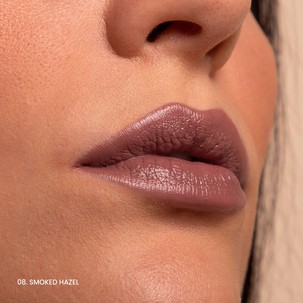 Primo piano di labbra truccate con un rossetto marrone rosato. Sotto le labbra c'è scritto "08. SMOKED HAZEL".