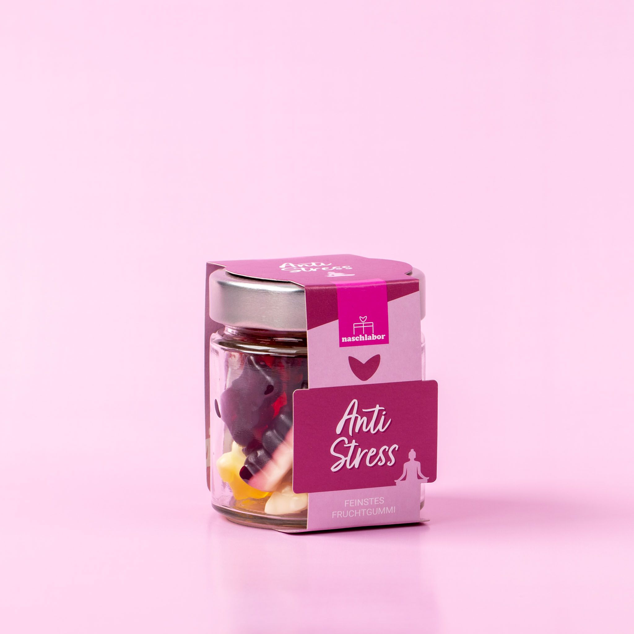 Glas mit Fruchtgummi-Bären, Etikett "Anti Stress". Rosa Hintergrund.