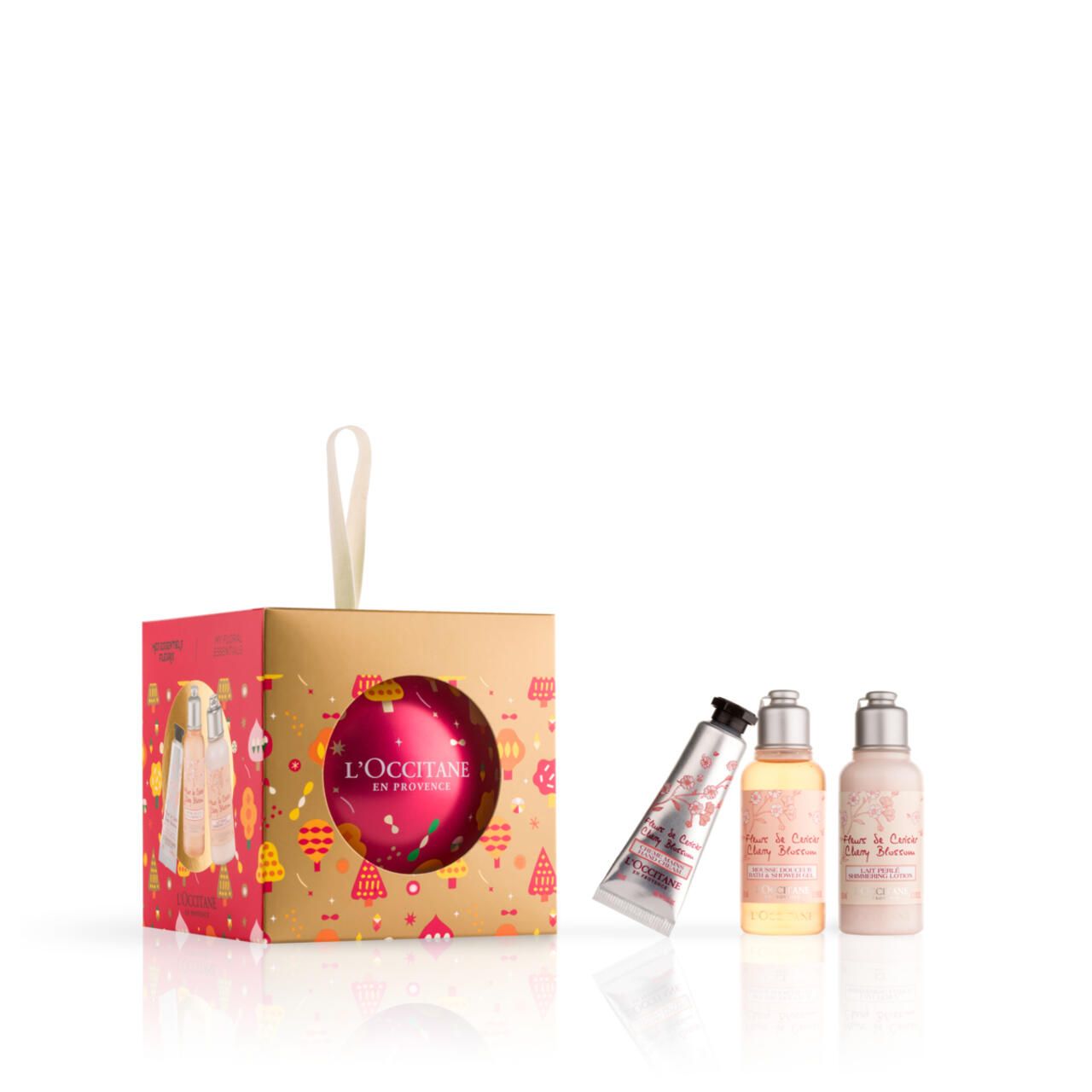 Geschenkset mit Kirschblüte-Produkten. Enthält Duschgel, Körpermilch, Handcreme und eine Weihnachtskugel-Verpackung mit L'Occitane-Logo.