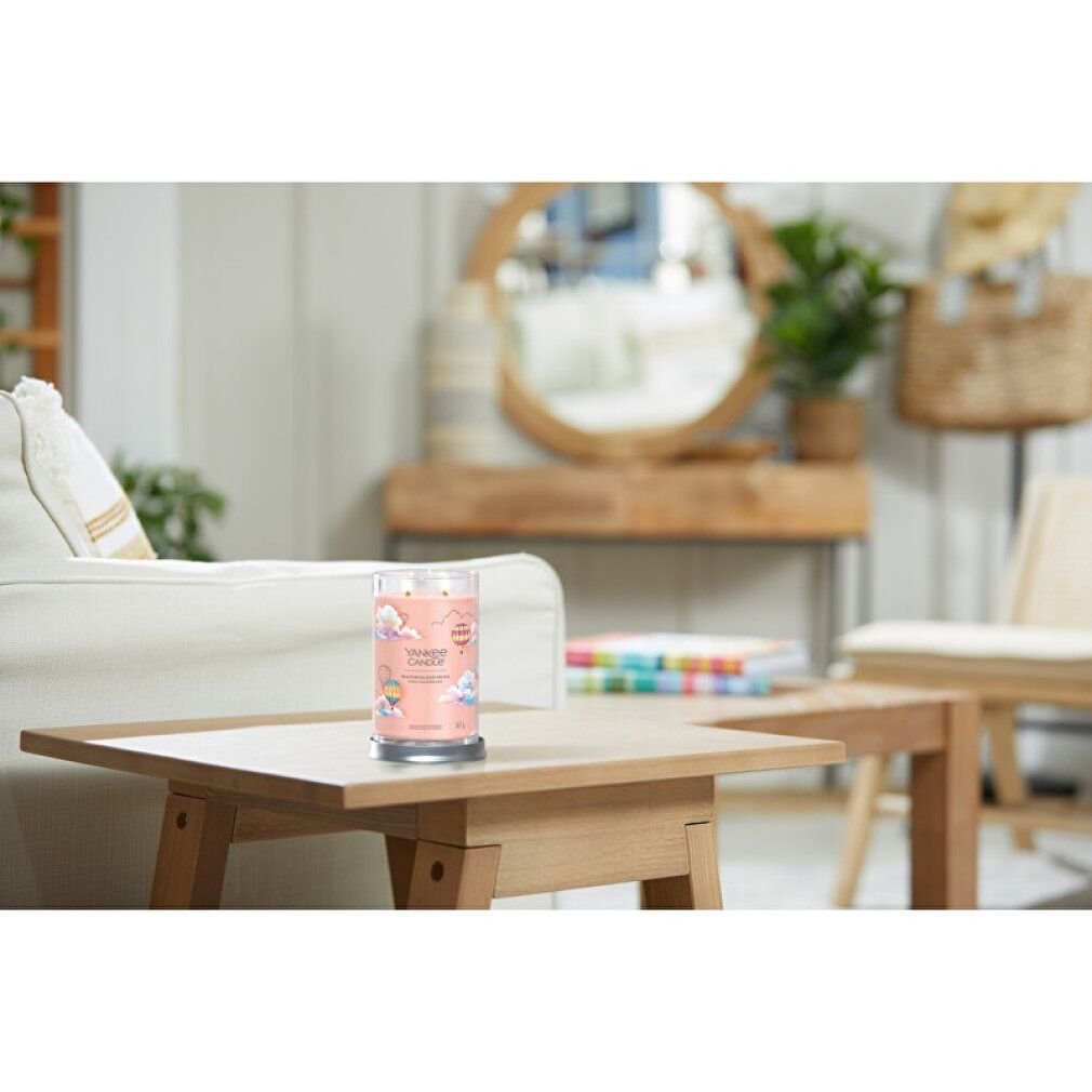 Yankee Candle-Becher auf einem Holztisch. Im Hintergrund: Sofa, Spiegel, Pflanzen. Produktetikett mit Text: Watercolour Skies.