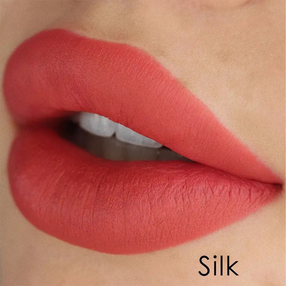 Nahaufnahme von Lippen, die mit einem korallenfarbenen Lippenstift bemalt sind. Der Name "Silk" ist am unteren Rand sichtbar.