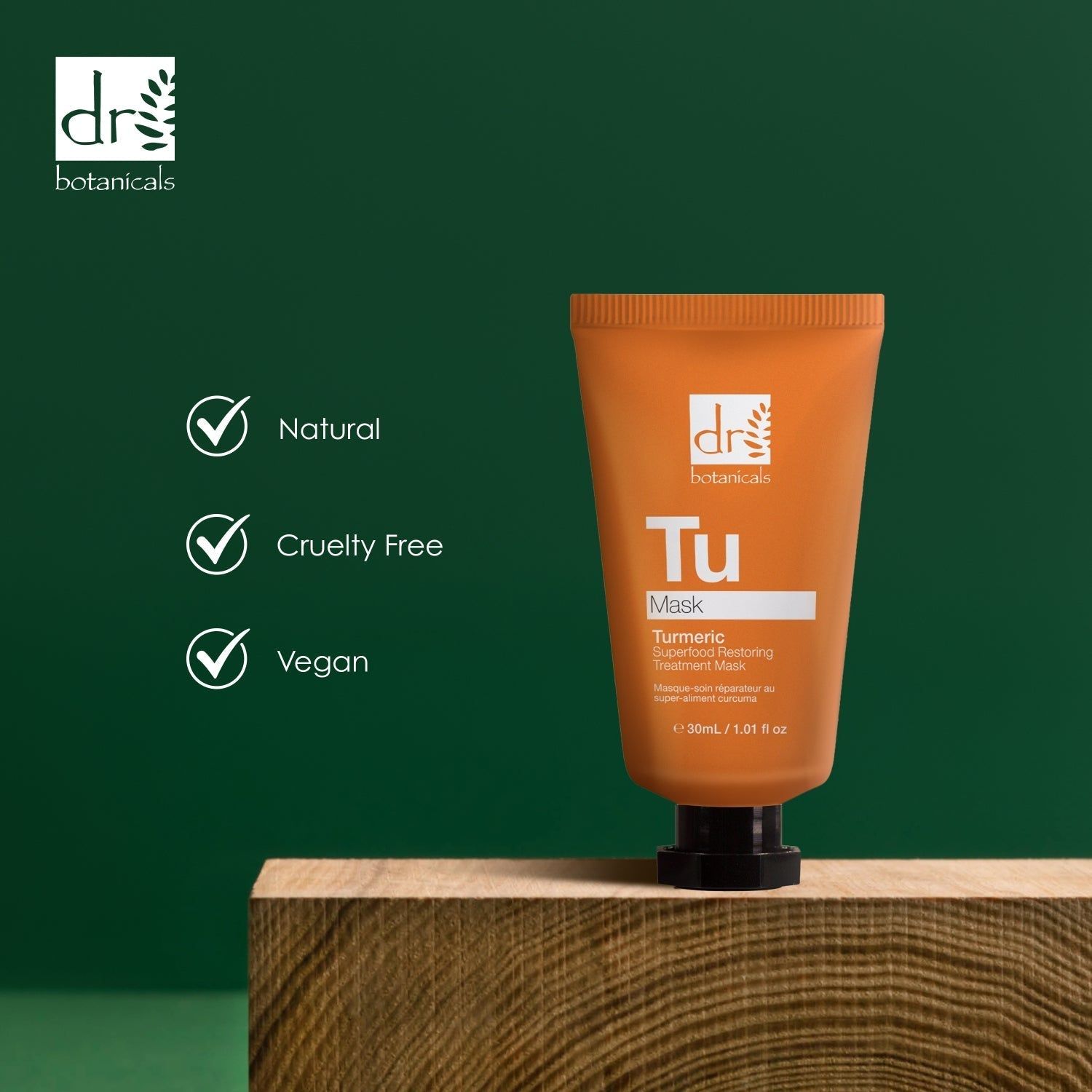 Orange Tube auf Holzblock. Logos: Natural, Cruelty Free, Vegan. Marke: Dr Botanicals. Hintergrund: Grün.